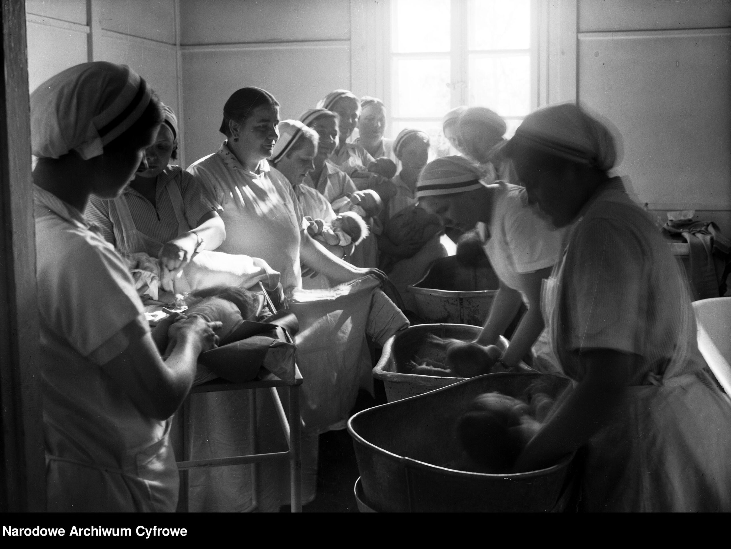 Czarno-białe archiwalne zdjęcie Uczennice Szkoły położnych podczas mycia i ważenia noworodków