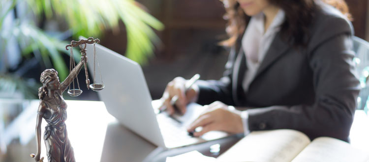 Kobieta pracuje na laptopie, siedzi przy biurku