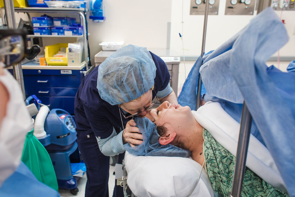 Położna całująca w czoło, kobietę rodzącą.